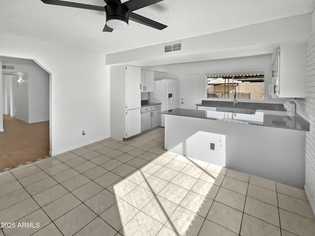 kitchen with white cabinets, light tile patterned floors, ceiling fan, kitchen peninsula, and a textured ceiling