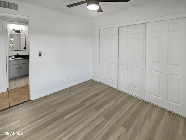 unfurnished bedroom with ceiling fan, sink, light hardwood / wood-style floors, and a closet