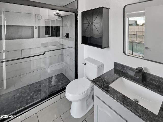 bathroom featuring a shower with door, vanity, tile patterned flooring, and toilet