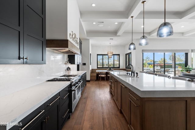 kitchen featuring a large island, hanging light fixtures, light stone countertops, double oven range, and a sink