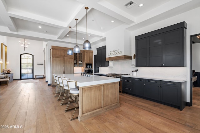 kitchen featuring visible vents, a spacious island, a kitchen breakfast bar, high end stainless steel range, and hanging light fixtures