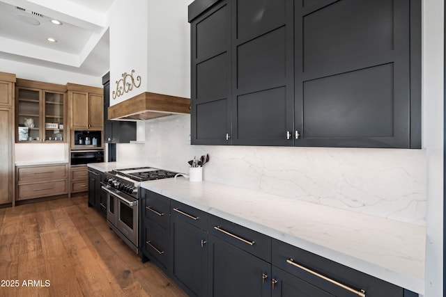 kitchen with range with two ovens, wall oven, premium range hood, dark wood-style floors, and tasteful backsplash