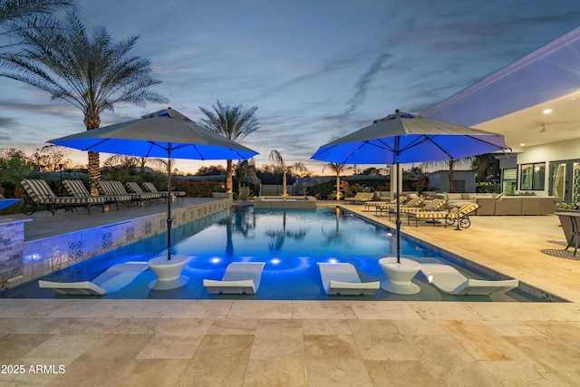 pool at dusk with an outdoor living space and a patio area