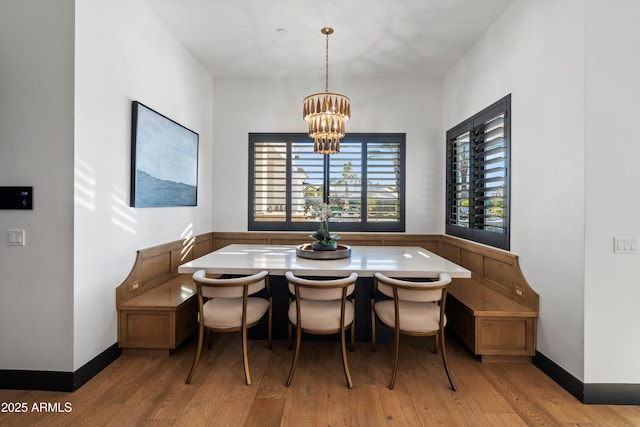 dining area with breakfast area, light wood-style floors, baseboards, and an inviting chandelier