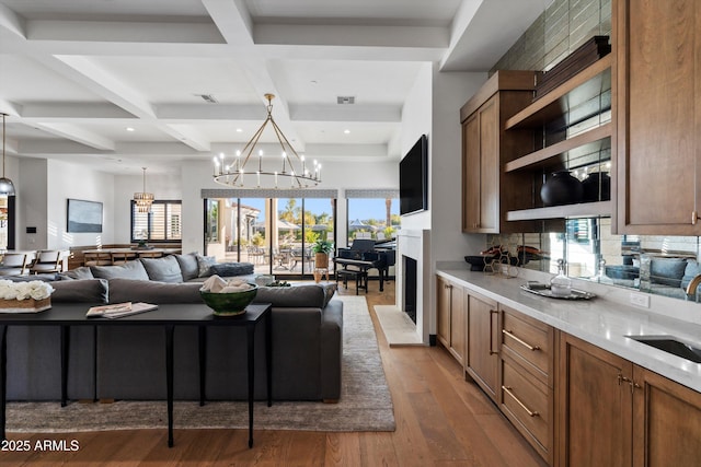 kitchen with hanging light fixtures, an inviting chandelier, open floor plan, wood finished floors, and coffered ceiling