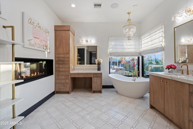 full bathroom featuring a notable chandelier, vanity, visible vents, a freestanding bath, and tile patterned floors