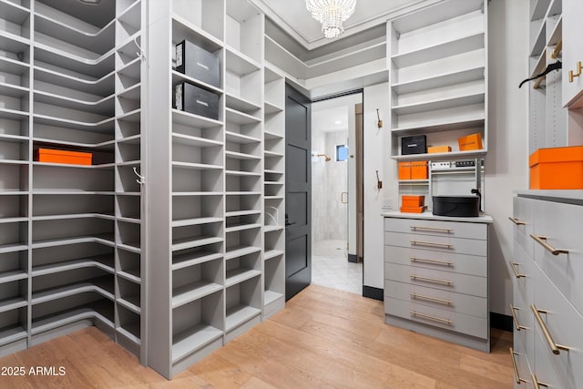 spacious closet with a chandelier and light wood finished floors