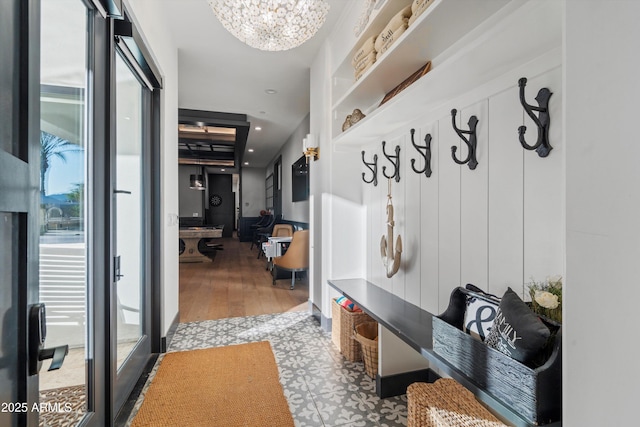 mudroom with wood finished floors and an inviting chandelier