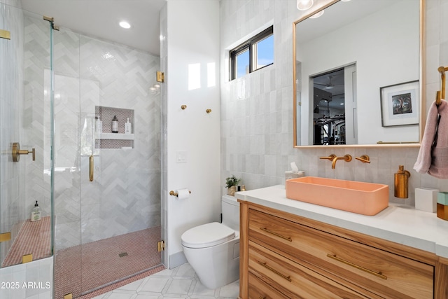 bathroom featuring toilet, tile walls, vanity, backsplash, and a stall shower