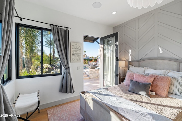 bedroom featuring access to exterior, recessed lighting, a decorative wall, light wood-type flooring, and baseboards