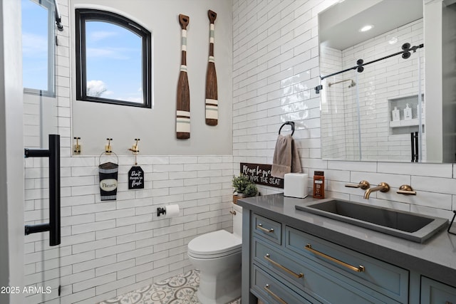 full bathroom featuring tiled shower, toilet, tile walls, and vanity