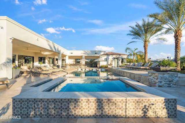 pool with a patio area and a hot tub