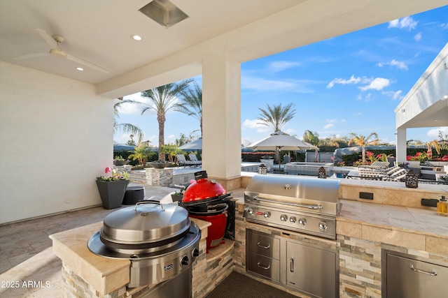 view of patio with grilling area, an outdoor kitchen, and a ceiling fan