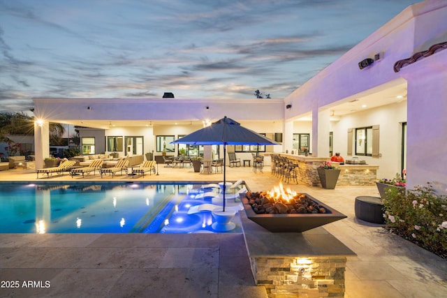 pool featuring a fire pit, outdoor dry bar, exterior kitchen, and a patio