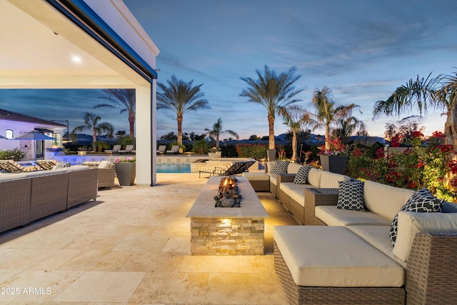 patio terrace at dusk featuring an outdoor pool and an outdoor living space with a fire pit