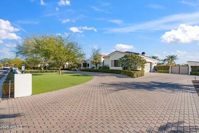 view of front of home featuring decorative driveway, an attached garage, fence, a residential view, and a front lawn