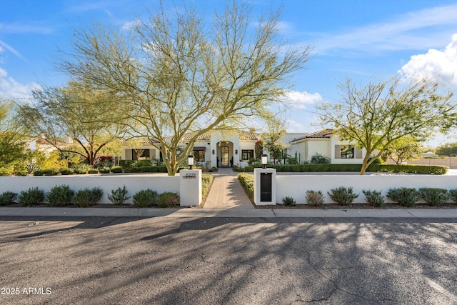 mediterranean / spanish house with a fenced front yard, a gate, and stucco siding