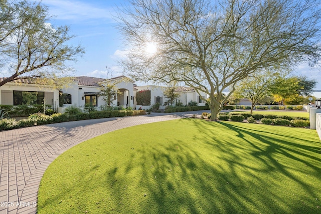 mediterranean / spanish-style house featuring a tiled roof, a front lawn, and stucco siding