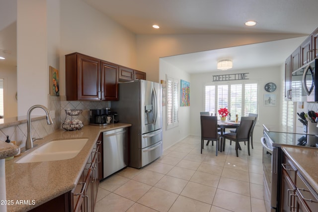 kitchen featuring vaulted ceiling, appliances with stainless steel finishes, light tile patterned flooring, tasteful backsplash, and sink