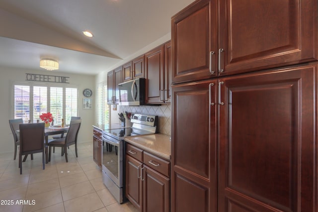 kitchen with lofted ceiling, light tile patterned floors, tasteful backsplash, and appliances with stainless steel finishes