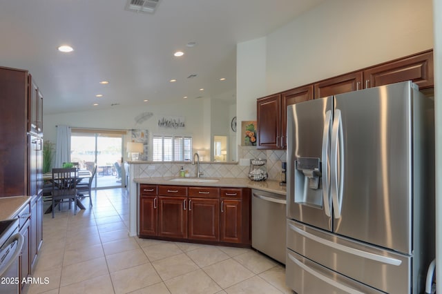 kitchen featuring lofted ceiling, sink, tasteful backsplash, kitchen peninsula, and stainless steel appliances