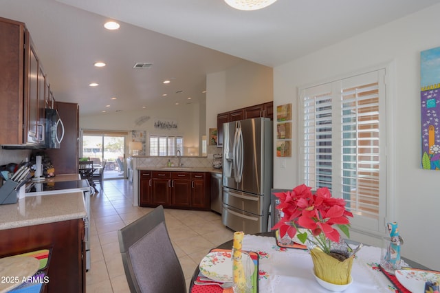 kitchen with tasteful backsplash, lofted ceiling, sink, kitchen peninsula, and stainless steel appliances