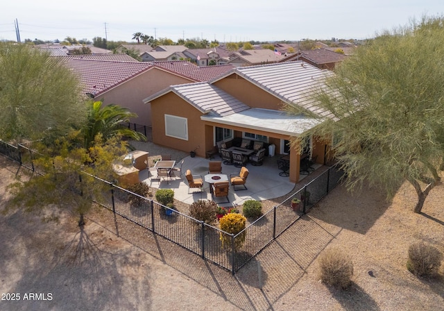 rear view of property featuring an outdoor living space with a fire pit and a patio