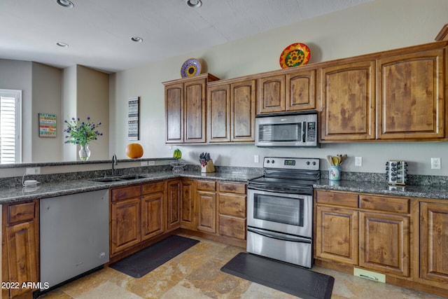 kitchen with light tile flooring, sink, stainless steel appliances, and dark stone counters