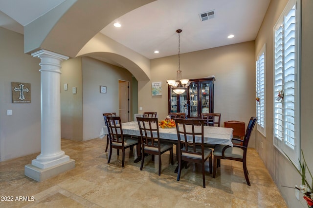 dining room with light tile flooring, decorative columns, a wealth of natural light, and an inviting chandelier