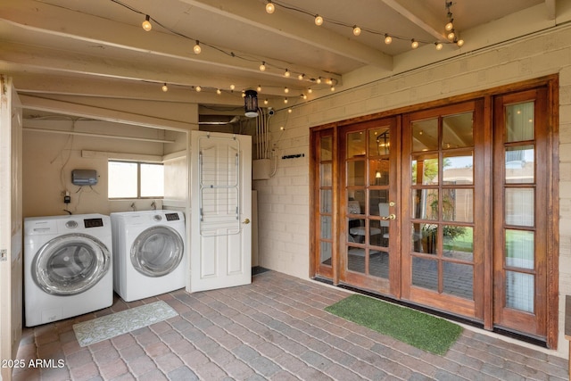 clothes washing area with independent washer and dryer, laundry area, and brick floor