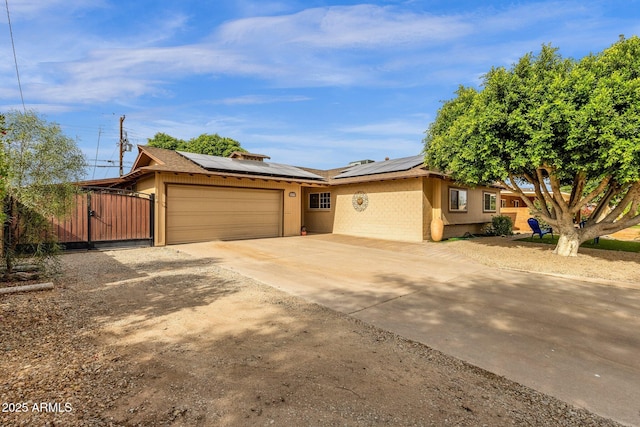 view of front of house with a garage, solar panels, a gate, and concrete driveway