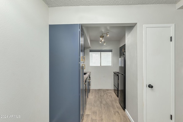 hallway featuring light wood-type flooring and a textured ceiling