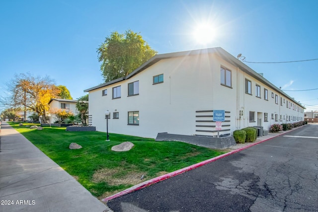 view of side of home featuring cooling unit and a yard