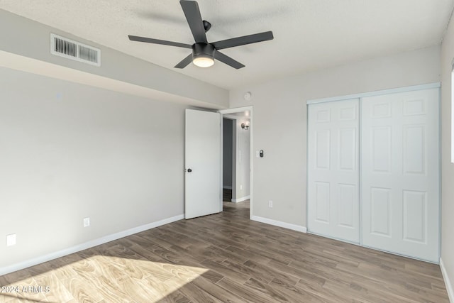 unfurnished bedroom featuring hardwood / wood-style floors, a textured ceiling, a closet, and ceiling fan