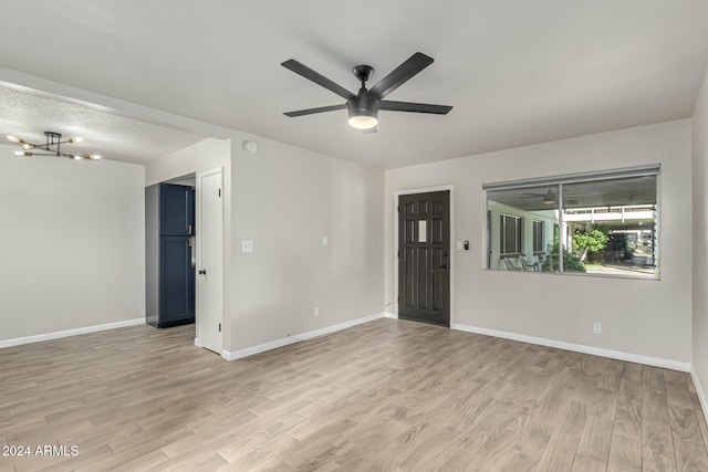 unfurnished room featuring light hardwood / wood-style floors and ceiling fan with notable chandelier