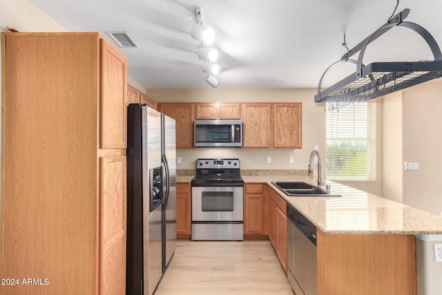 kitchen featuring track lighting, sink, light hardwood / wood-style flooring, light stone counters, and stainless steel appliances