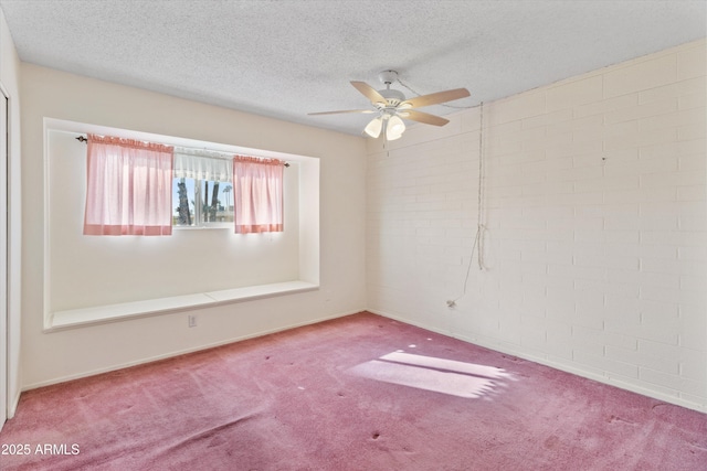 carpeted spare room featuring ceiling fan, a textured ceiling, and brick wall