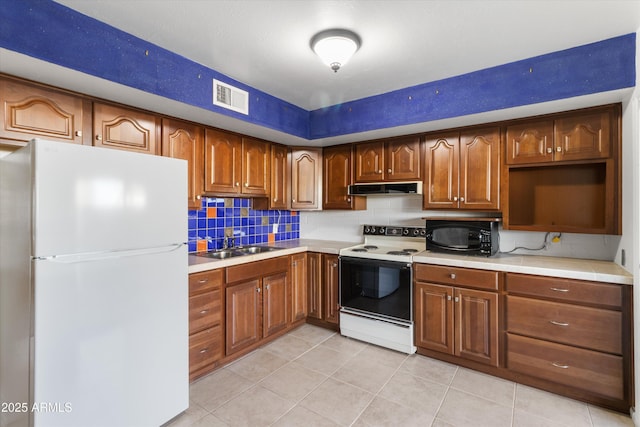 kitchen with decorative backsplash, light tile patterned flooring, white appliances, and sink