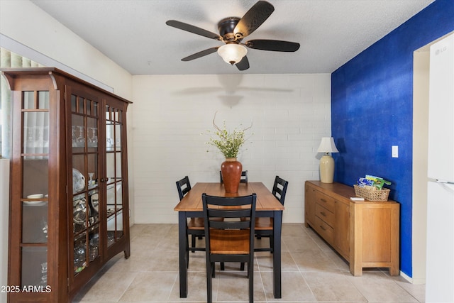 dining space featuring ceiling fan, brick wall, and a textured ceiling