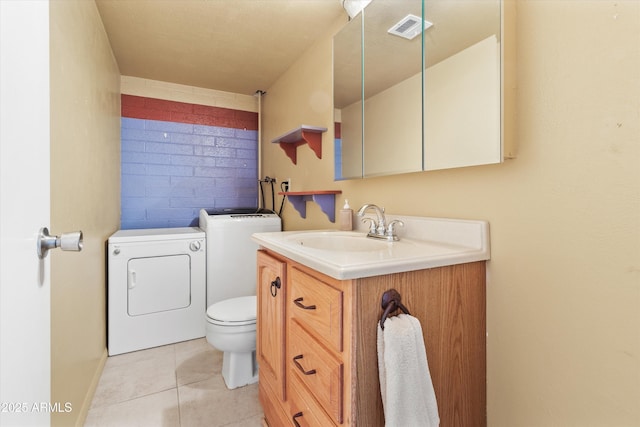 bathroom with toilet, vanity, tile patterned floors, and washing machine and clothes dryer