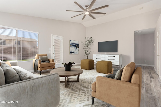 living area featuring lofted ceiling, ceiling fan, light wood-style flooring, and baseboards