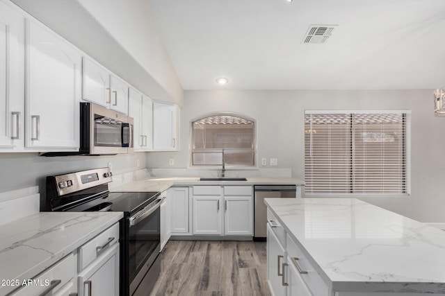 kitchen with appliances with stainless steel finishes, a sink, visible vents, and white cabinets