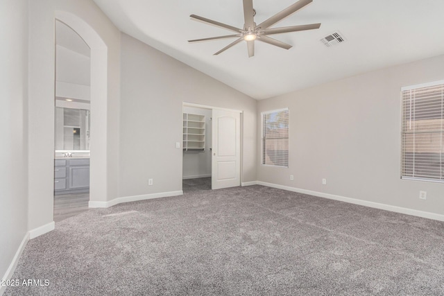 unfurnished bedroom featuring lofted ceiling, carpet floors, visible vents, baseboards, and ensuite bath