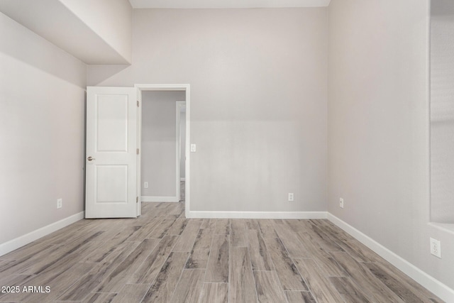 spare room featuring baseboards and wood finished floors