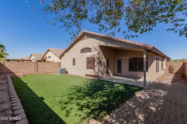 rear view of house with a fenced backyard, a yard, central air condition unit, a patio area, and stucco siding