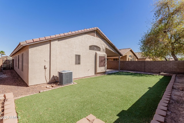 rear view of house with a fenced backyard, central AC, and stucco siding