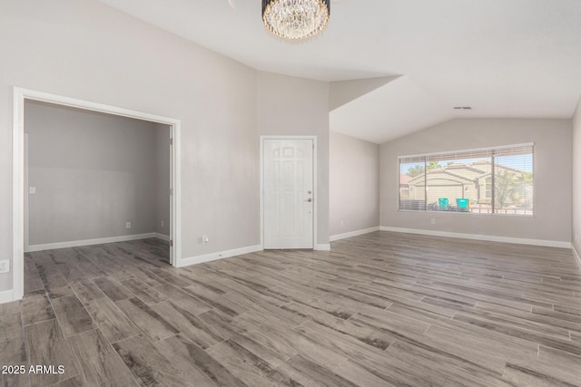 interior space with lofted ceiling, visible vents, a notable chandelier, and wood finished floors