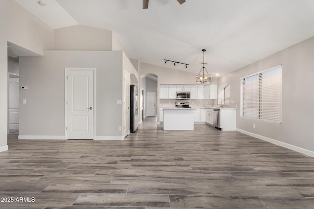 kitchen with lofted ceiling, white cabinets, stainless steel appliances, and open floor plan