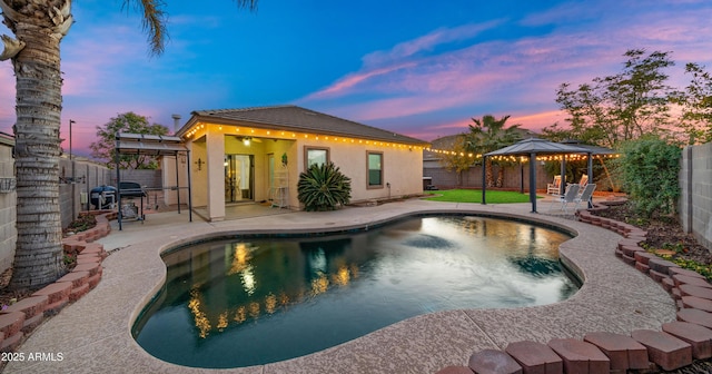 pool at dusk with a gazebo and a patio