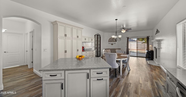 kitchen with dark hardwood / wood-style flooring, decorative light fixtures, stainless steel dishwasher, and a center island